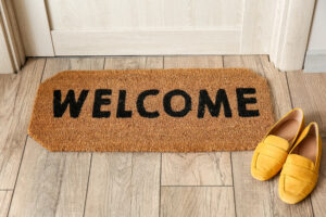 Mat with word WELCOME and female shoes near wooden door in hallway